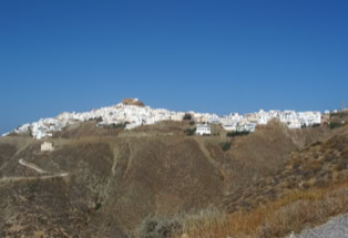 Blick von unten über karge Hänge auf die schneeweiße Hauptstadt auf der Spitze der insel anafi