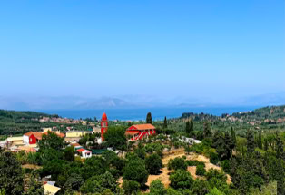 Blick vom Inselinneren über Olivenhaine mit roten Häuschen und Kirche, Korfu